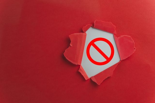 赤い背景から破られて見える注意マーク